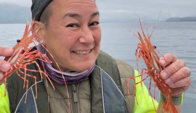 Genevieve Erin O’Brien on a boat holding up shrimp in each hand